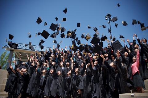 Photo of graduands throwing their hats to the air.
