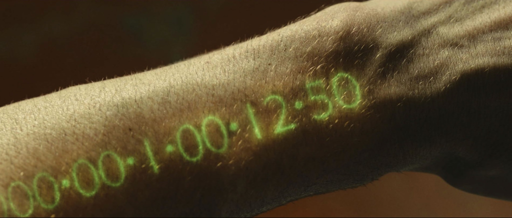Photo from movie In Time, where a watch in the arm shows how much time people have left before dying.
